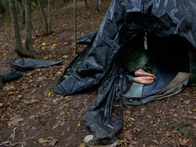 Seorang migran beristirahat di tenda yang dibuat dari lembaran plastik di kamp darurat di hutan di luar Velika Kladusa, Bosnia pada 25 September 2020. Bosnia menjadi salah satu tempat singgah para imigran dan pengungsi dalam perjalanannya ke Eropa Barat. (AP Photo/Kemal Softic)