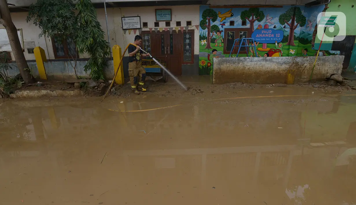 Petugas pemadam kebakaran menyemprotkan air untuk membersihkan lumpur sisa banjir di Kawasan Bukit Duri, Jakarta, Sabtu (4/1/2020). Meski banjir sudah mulai surut, jalan-jalan dan permukiman warga masih tertutup lumpur tebal. (merdeka.com/Imam Buhori)