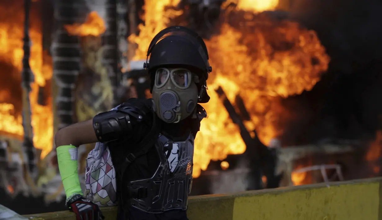 Demonstran anti-pemerintah di Venezuela mengenakan masker saat menggelar aksi di Caracas, Venezuela, Sabtu (26/5). Memasuki hari ke-56, aksi demonstrasi anti-pemerintah tersebut telah memakan korban jiwa 47 orang. (AP Photo)  