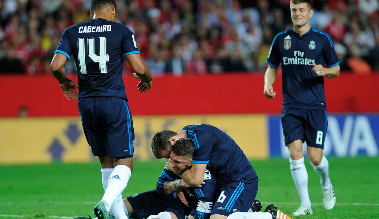 Sergio Ramos disambut-rekan-rekannya setelah melakukan tendangan salto yang berbuah gol ke gawang Sevilla dalam laga La Liga Spanyol di Stadion Ramon Sanchez Pizjuan, Sevilla, Senin (9/11/2015) dini hari WIB. (AFP Photo/Cristina Quicler)