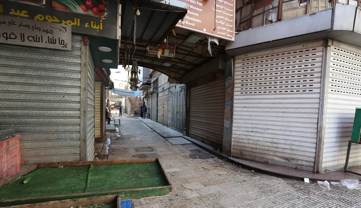 Pemuda Palestina berdiri di depan toko-toko yang tutup selama pemogokan umum di Nablus di Tepi Barat yang diduduki, sehari setelah sebuah roket menghantam rumah sakit Gaza yang menewaskan ratusan orang, Rabu (18/10/2023). (Zain JAAFAR / AFP)