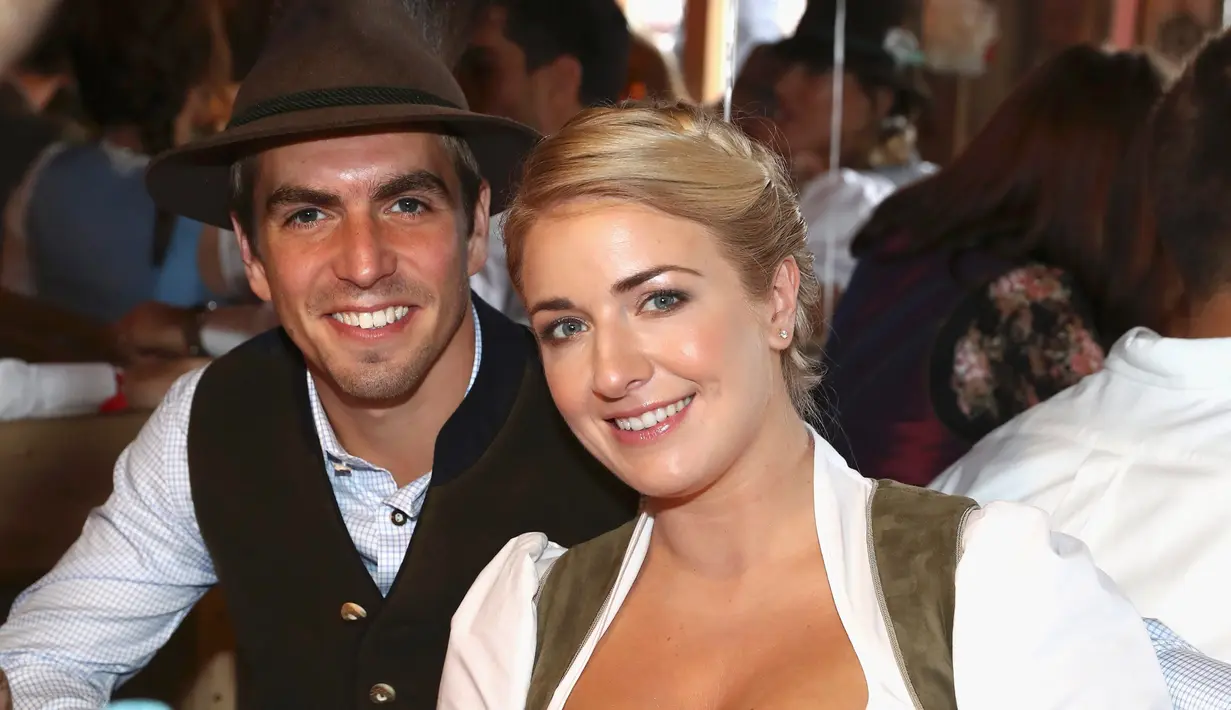 Kapten Bayern Munchen, Philipp Lahm bersama istrinya Claudia tersenyum saat menghadiri acara Oktoberfest di Munich, Jerman (2/9). (REUTERS/Alexander Hassenstein)