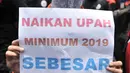 Seorang buruh membawa poster berisi tuntutan kenaikan upah sebesar 30 persen saat menggelar unjuk rasa di depan Gedung Ketenagakerjaan, Jakarta, Rabu (24/10). (Merdeka.com/Iqbal S. Nugroho)