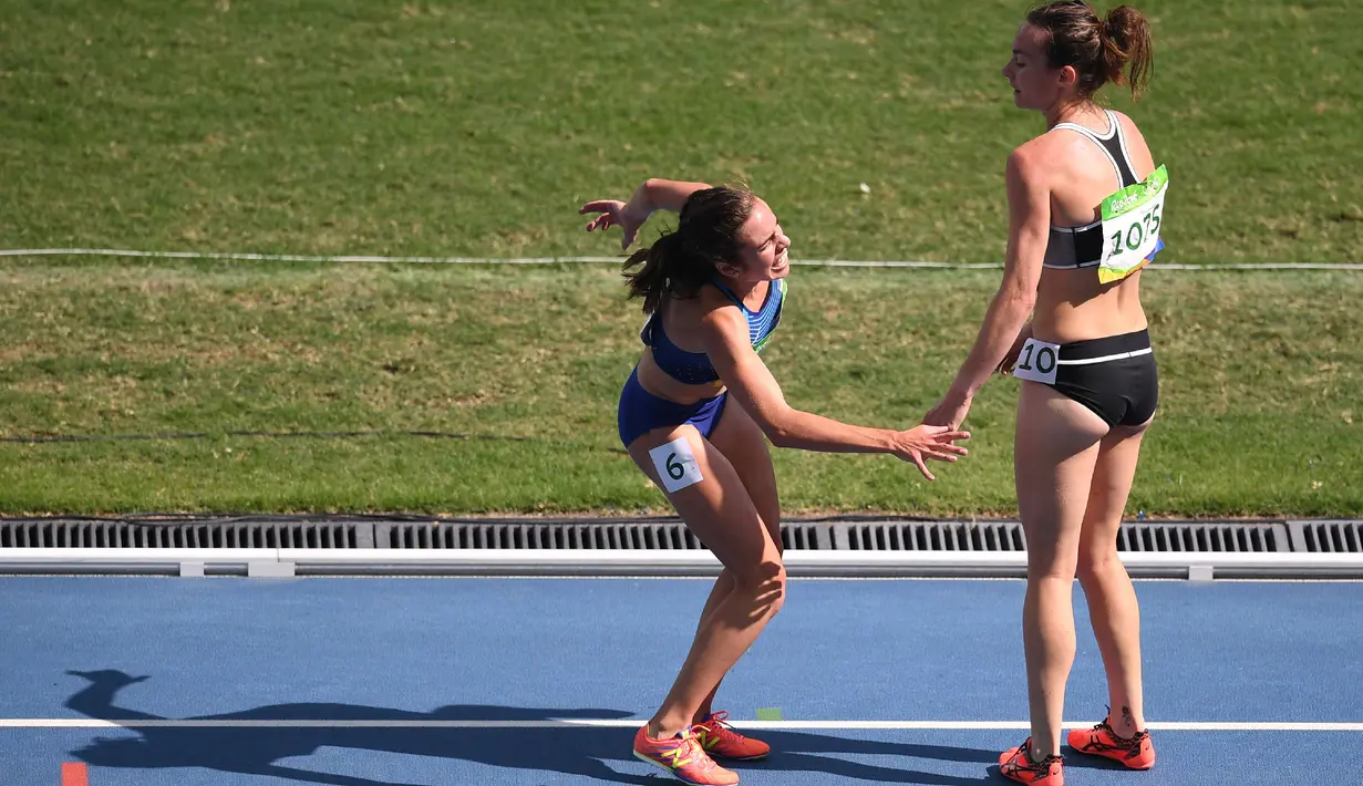 Pelari asal Selandia Baru, Nikki Hamblin membantu rivalnya, yaitu pelari asal AS, Abbey D’Agostino yang jatuh ketika terjadi insiden tabrakan saat penyisihan lomba lari 5.000 meter putri Olimpiade 2016. (AFP PHOTO/Johannes EISELE)