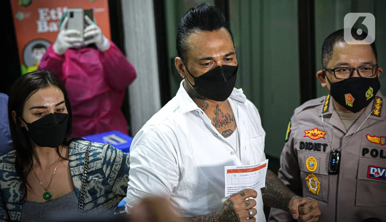 Musikus I Gede Ary Astina alias Jerinx  menunjukkan kartun vaksin covid-19 usai menerima suntikan di Biddokkes Polda Metro Jakarta, Sabtu (15/8/2021). Jerinx akhirnya memutuskan untuk menerima suntikan vaksin Sinovac dosis pertama. (Liputan6.com/Faizal Fanani)
