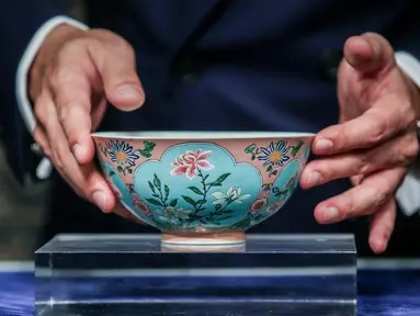 Wakil Kepala Sotheby Asia, Nicolas Chow memegang mangkuk langka dari masa Dinasti Qing pada pratinjau media di Hong Kong, Selasa (3/4). Mangkuk antik kepunyaan Kaisar Kangxi itu terjual dengan harga USD 30,4 juta (Rp 417 miliar). (ISAAC LAWRENCE/AFP)