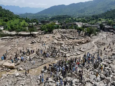 Pemandangan dari udara menunjukkan para korban banjir berkumpul di dekat rumah-rumah yang rusak di sepanjang tepi sungai yang dikelilingi batu-batu besar di distrik Buner, provinsi Khyber Pakhtunkhwa, Pakistan pada 17 Agustus 2025. (Abdul MAJEED/AFP)