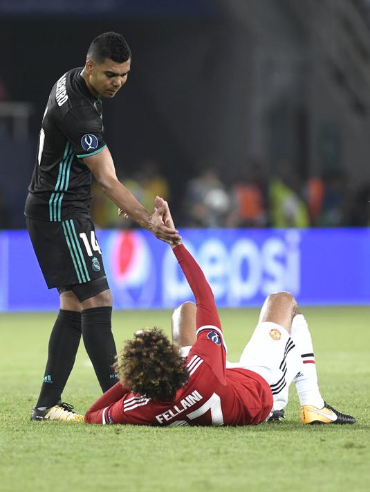 Gelandang Real Madrid, Casemiro, membantu gelandang Manchester United, Marouane Fellaini, pada laga Piala Super Eropa di Stadion Philip II, Skopje, Selasa (8/8/2017). Foto muka unik Fellaini viral di media sosial. (AFP/Nikolay Doychinov)