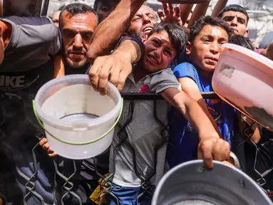 Warga Palestina berdesakan berebut makanan yang sudah dimasak dari dapur umum di Jabalia, Jalur Gaza Utara, pada 17 Mei 2025. (Bashar TALEB/AFP)