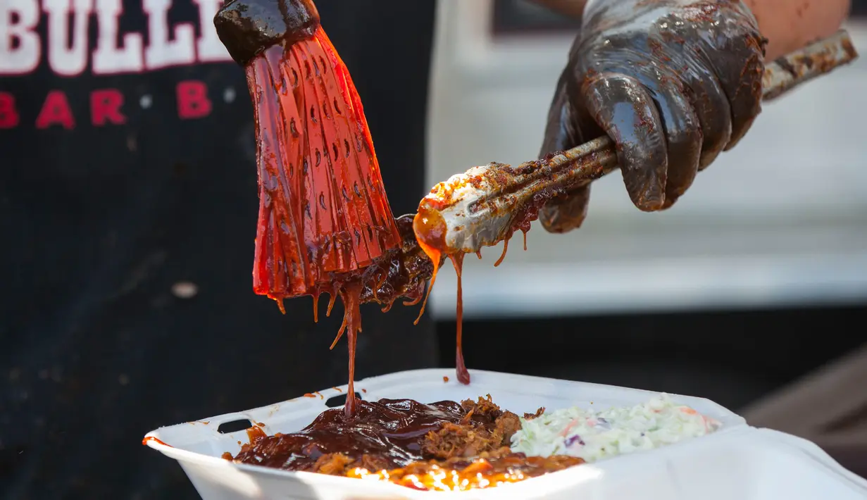 Koki menambahkan saus barbeku pada iga yang sudah dimasak dalam acara drive-thru Scarborough Ribfest 2020 di Toronto, Kanada, 27 September 2020. Pengunjung festival makanan yang digelar dalam format drive-thru itu dapat memesan makanan dari penjual di lokasi dan membawanya pulang. (Xinhua/Zou Zheng)