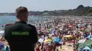 Petugas layanan ambulans memandangi kerumunan pengunjung yang berkumpul di pantai di Bournemouth, Kamis (25/6/2020). Pantai tersebut diserbu warga Inggris, setelah masa pelonggaran pembatasan sosial akibat covid-19 dan pembatasan perjalanan Eropa. (Andrew Matthews/PA via AP)