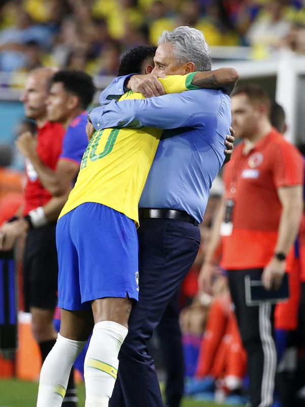 Penyerang Brasil, Neymar Jr memeluk pelatih Tite usai mencetak gol ke gawang Kolombia selama laga uji coba di Hard Rock Stadium, Florida (7/9/2019). Gol neymar pada menit ke-58 ini menjadi penyelamat Brasil. (AFP Photo/Rhona Wise)