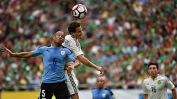 Pemain Uruguay, Carlos Sanchez, duel udara dengan pemain Meksiko, Andres Guardado, pada laga Grup C Copa Amerika. Keunggulan Meksiko tercipta melalui bunuh diri Alvaro Pereira serta gol dari Rafale Marquez dan Hector Herrera. (AFP/Nelson Almeida)