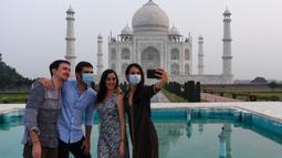 Turis berfoto dengan latar belakang Taj Mahal di Agra, India pada Senin (21/9/2020). Taj Mahal kembali dibuka untuk umum hari ini, Senin (21/9), saat negara dengan 1,3 miliar orang itu telah mencatat lebih dari 5,4 juta kasus Covid-19. (Sajjad HUSSAIN/AFP)