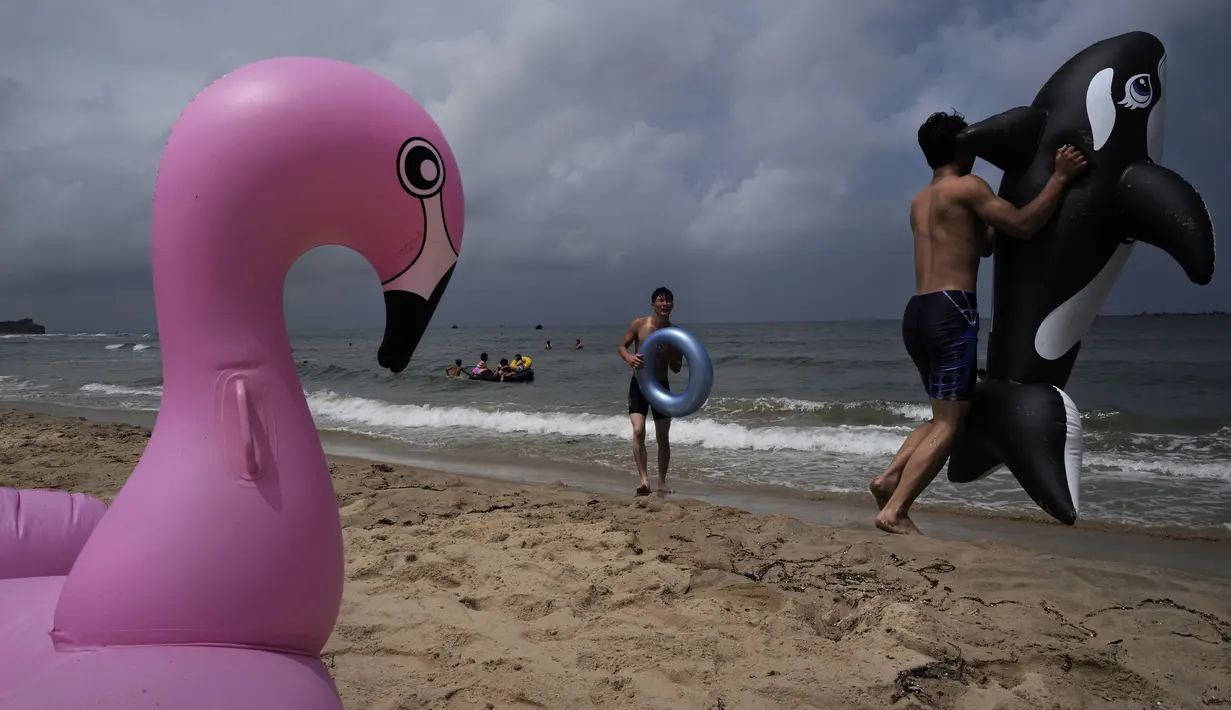 <p>Seorang pria bermain dengan ban karet lumba-lumba di pantai Sijung Ho di Korea Utara (14/7/2019). Pantai Sijung Ho merupakan tujuan wisata populer bagi penduduk lokal dan asing. (AP Photo/Vincent Yu)</p>