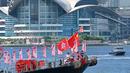 Sebuah kapal nelayan dengan spanduk dan bendera untuk menandai peringatan 25 tahun penyerahan Hong Kong dari Inggris ke China berlayar melalui pelabuhan Victoria Hong Kong (28/6/2022). (AFP/Peter Parks)