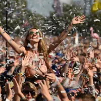 Pengunjung wanita berjoget saat menyaksikan konser selama Festival Glastonbury di Worthy Farm, Somerset, Inggris (30/6/2019). Gelombang panas yang melanada bagian-bagian Eropa tidak menyurutkan pengunjung untuk berkumpul di festival ini. (AP Photo/Joel C Ryan)