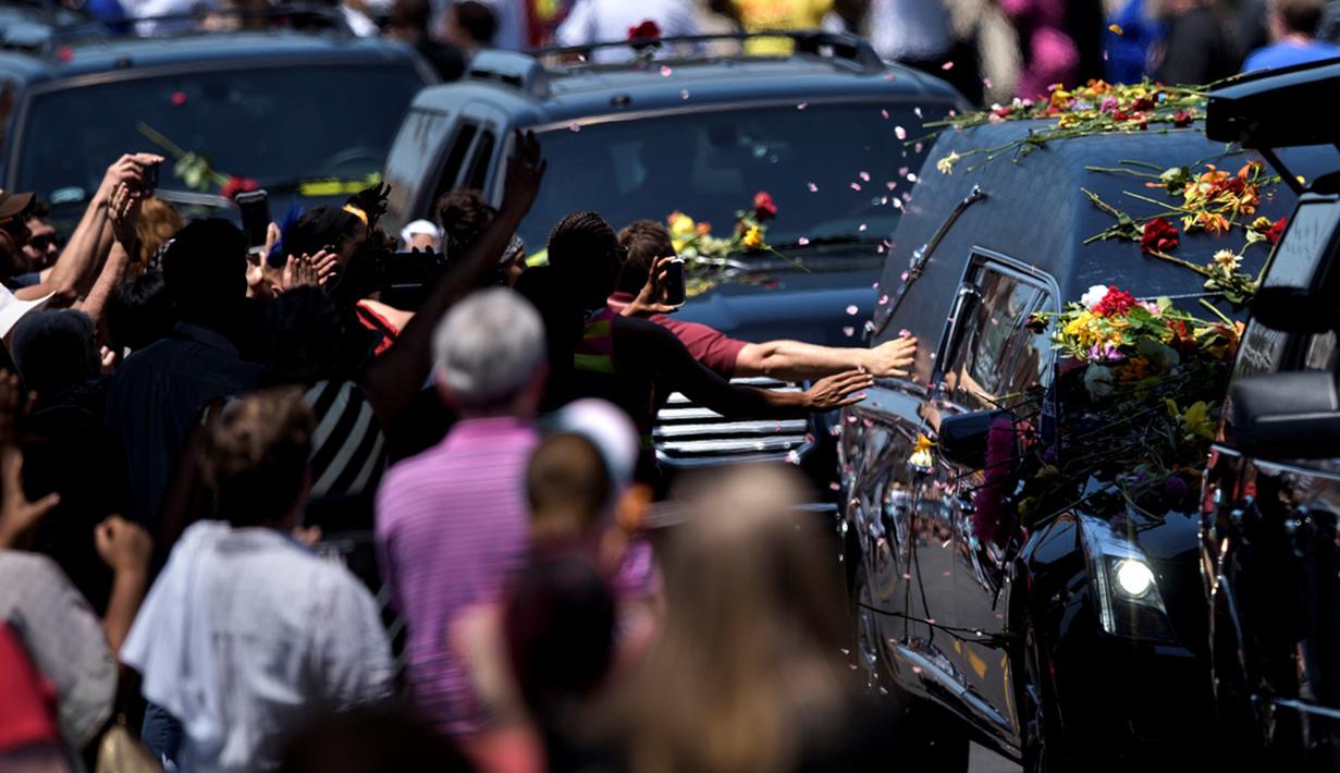 Beberapa orang berusaha menyentuh mobil jenazah Muhammad Ali menuju pemakaman Cave Hill di Louisville, Kentucky, AS, (10/6/2016). Ribuan orang memberi penghormatan terakhir di sepanjang jalan menuju pemakaman. (AFP/Brendan Smialowski)