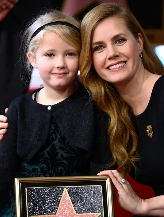 Amy Adams bersama anaknya berpose dengan plakat penghargaan dari Hollywood Walk of Fame di Los Angeles, AS, Kamis (12/1). Adams menerima plakat penghormatan atas perannya di film fiksi ilmiah Paramount Pictures Arrival. (AP Photo/ Rich Fury)
