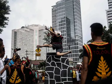 Atraksi seorang pria saat melakukan fahombo atau lompat batu dalam sebuah acara pagelaran seni dan kebudayaan Nias di Jalan Imam Bonjol, Jakarta, Minggu (12/2). Pagelaran ini diselenggarakan oleh Pemuda Peduli Nias. (Liputan6.com/Faizal Fanani)