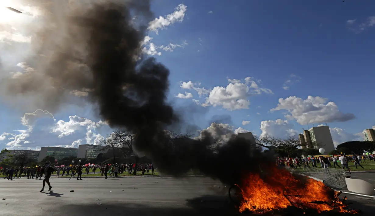 Demonstran membakar kursi yang diambil dari gedung Kementerian Pertanian dalam unjuk rasa anti-pemerintah di Brasilia, Brasil, Rabu (24/5). Ribuan demonstran bergerak ke ibu kota menuntut pengunduran diri Presiden Michel Temer. (AP Photo/Eraldo Peres)