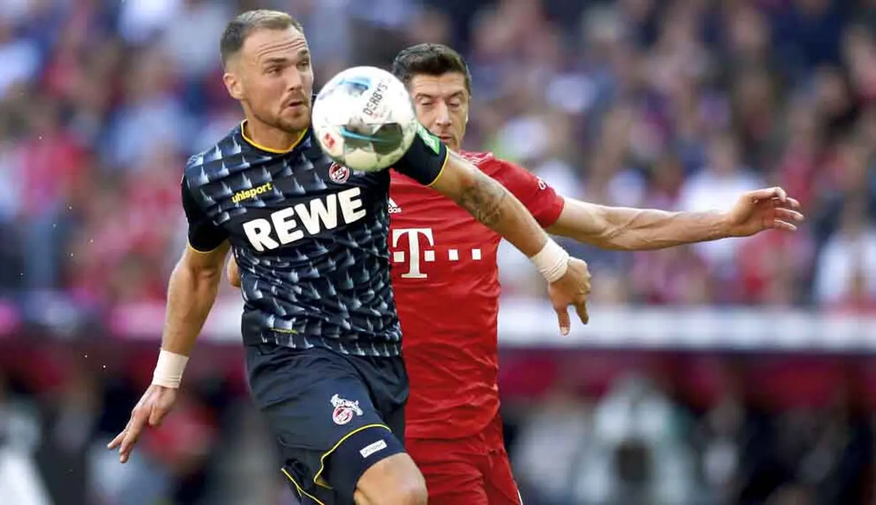 Striker Bayern Munchen, Robert Lewandowski, berebut bola dengan pemain Koln, Rafael Czichos, pada laga Bundesliga di Allianz Arena, Sabtu (21/9/2019). Bayern Munchen menang 4-0 atas Koln. (AP/Matthias Schrader)