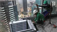 Pekerja Nusa Konstruksi Enjiniring memasang kaca gedung World Capital Tower, di Mega Kuningan, Jakarta, Rabu (13/9). Deretan gedung perkantoran masih menghiasi di ibukota Jakarta. (Liputan6.com/Fery Pradolo)