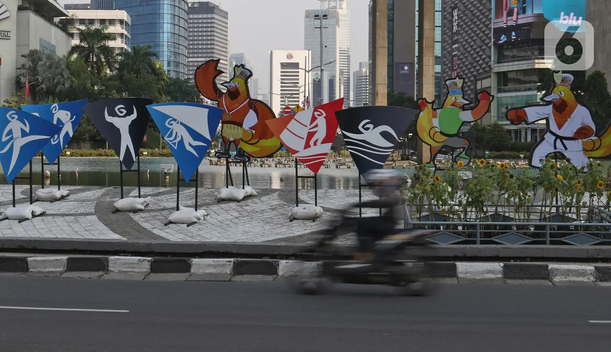 Pengendara sepeda motor melintas di dekat maskot Pekan Olahraga Nasional (PON) XX Papua di Bundaran Hotel Indonesia, Jakarta, Jumat (16/07/2021). Presiden Joko Widodo memastikan PON XX Papua tetap akan berlangsung pada 2-15 Oktober 2021. (Liputan6.com/Herman Zakharia)
