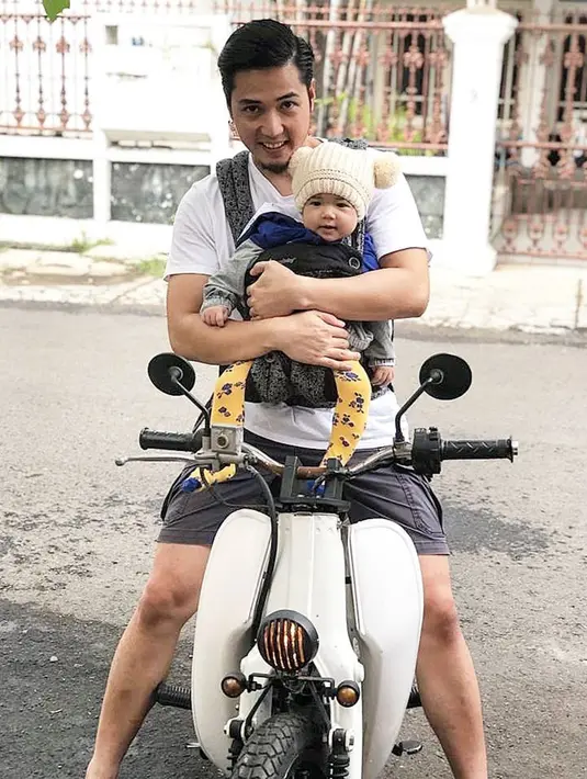 Dengan motor lawasnya, Kinos berusaha menggendong mesra sang anak untuk menikmati sore hari dengan berjalan-jalan santai di kawasan rumahnya. Bila diperhatikan dari cara menggendong Kinos, ia begitu hati-hati saat mengajak anaknya tersebut jalan-jalan menggunakan motor. (Liputan6.com/IG/@kinosnoski)