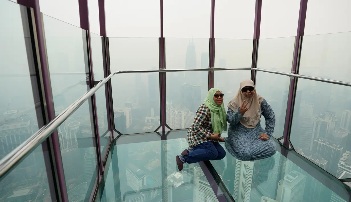 Wisatawan berpose di skybox Kuala Lumpur Tower dengan pemandangan kabut asap pekat yang menyelimuti Kuala Lumpur, Malaysia, Jumat (13/9/2019).  Kabut asap yang menyelimuti sejumlah wilayah di Malaysia diduga berasal dari kebakaran hutan di Indonesia. (AP Photo/Vincent Thian)