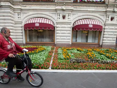 Seorang pria bersepeda melewati deretan bunga dalam festival bunga tahunan di pusat perbelanjaan GUM di dekat Lapangan Merah, pusat Kota Moskow, Rusia, pada 15 Juli 2020. Sekitar 200.000 bunga ditanam di dalam dan luar pusat perbelanjaan tersebut pada tahun ini. (Xinhua/Alexander Zemlianichenko Jr)