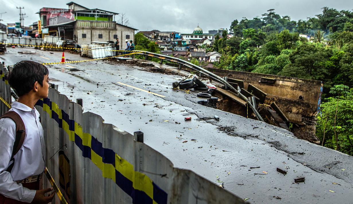 Seorang anak laki-laki melihat lokasi longsor akibat hujan deras di kawasan Caringin, Bogor, Jawa Barat, Kamis (2/32023). Longsor mengakibatkan jalan nasional yang menghubungkan Bogor dan Sukabumi itu hanya dapat dilalui satu lajur kendaraan. (ADITYA AJI/AFP)