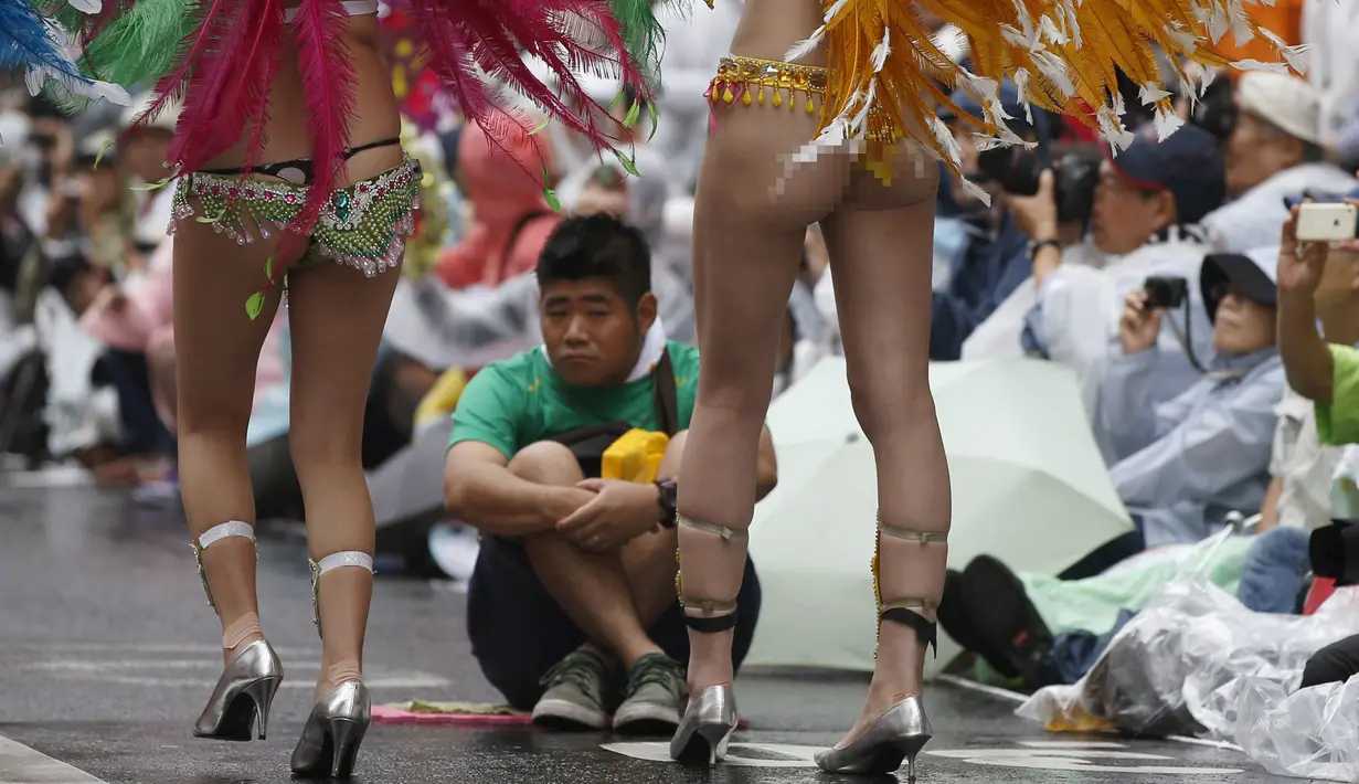 Penari samba berjalan melelwati petugas keamanan saat acara tahunan Karnaval Asakusa Samba ke-34 di Tokyo, Jepang, 29 Agustus 2015. Sekitar 5.000 orang berpartisipasi dalam karnaval terbesar yang ada di Jepang ini. (REUTERS/Toru Hanai)