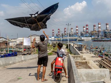 Anak-anak menerbangkan layang-layang saat bermain di sepanjang tanggul laut yang dibangun di desa pesisir Tambaklorok, di Semarang, Jawa Tengah, pada 17 Juni 2025. (DEVI RAHMAN/AFP)