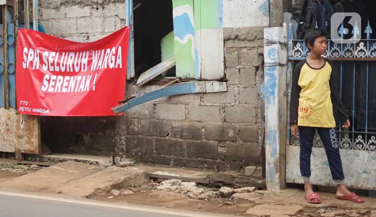 Seorang anak berdiri dekat poster protes warga terhadap pembangunan flyover di kawasan Tanjung Barat, Jakarta, Rabu (15/7/2020). Dalam poster protes tersebut, warga menuntut agar pembayaran pelunasan pembebasan lahan segera diselesaikan secara serentak. (Liputan6.com/Immanuel Antonius)
