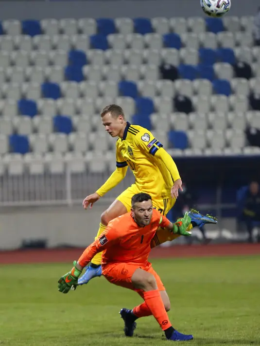 Kiper Kosovo Samir Ujkani (bawah) memperebutkan bola dengan pemain Swedia Viktor Claesson pada pertandingan Grup B kualifikasi Piala Dunia 2022 di Stadion Fadil Vokrri, Pristina, Kosovo, Minggu (28/3/2021). Swedia menang 3-0. (AP Photo/Visar Kryeziu)