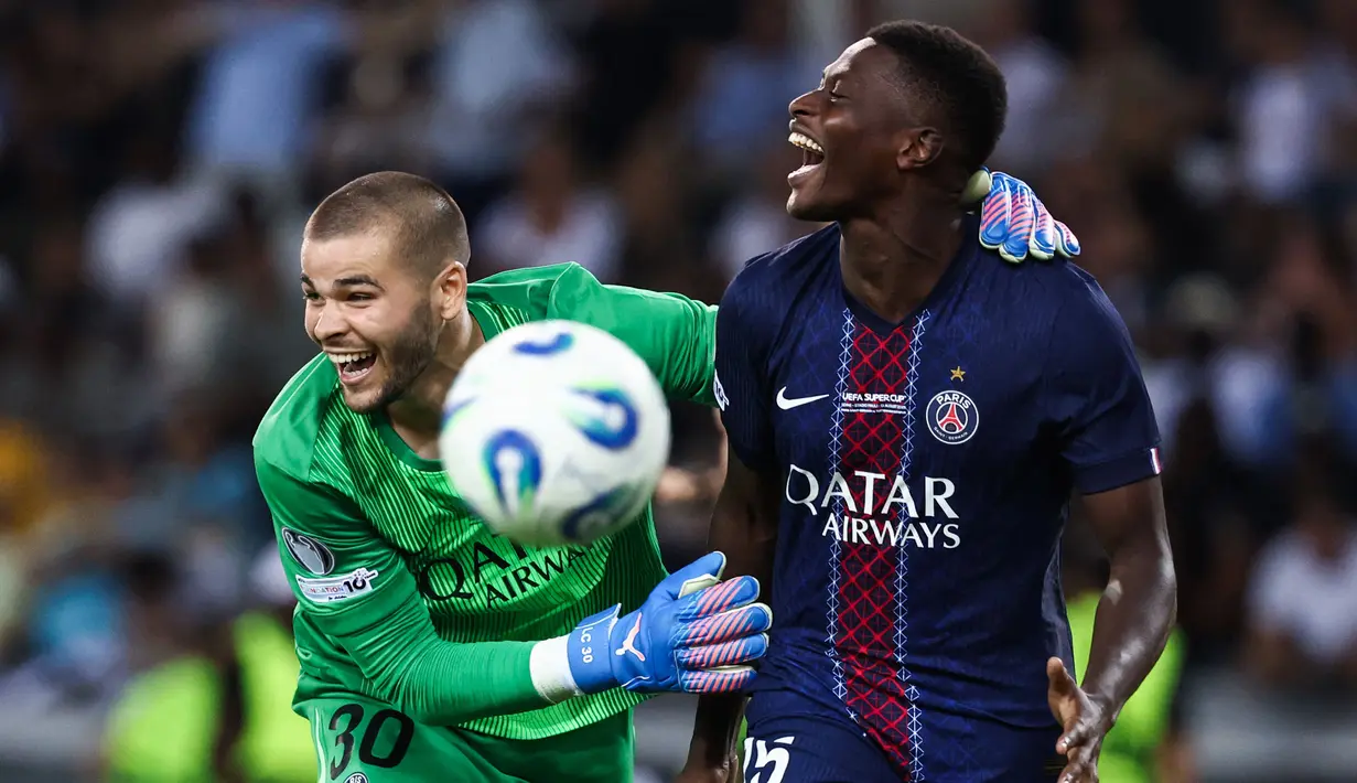 Pemian PSG, Nuno Mendes (kanan) bersama kiper Lucas Chevalier merayakan kemenangan dalam babak adu penalti laga final UEFA Super Cup melawan Tottenham Hotspur yang berlangsung di Bluenergy Stadium, Udinese, Italia, Rabu (13/08/2025) waktu setempat. (AFP/Franck Fife)