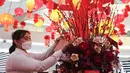 Seorang wanita menaruh amplop di Instalasi Red Lunar di Mal Senayan City, Jakarta, Kamis (19/1/2023). Instalasi tersebut bernuansa merah dan sentuhan emas, yang berisi Mei Hwa forest hingga Lantern towers dengan ratusan juntaian lampion indah. (Liputan6.com/Herman Zakharia)