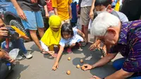 Warga mencoba memberdirikan telur saat Festival Peh Cun di Tangerang, Kamis (22/6/2023). (Liputan6.com/ Pramita Tristiawati)