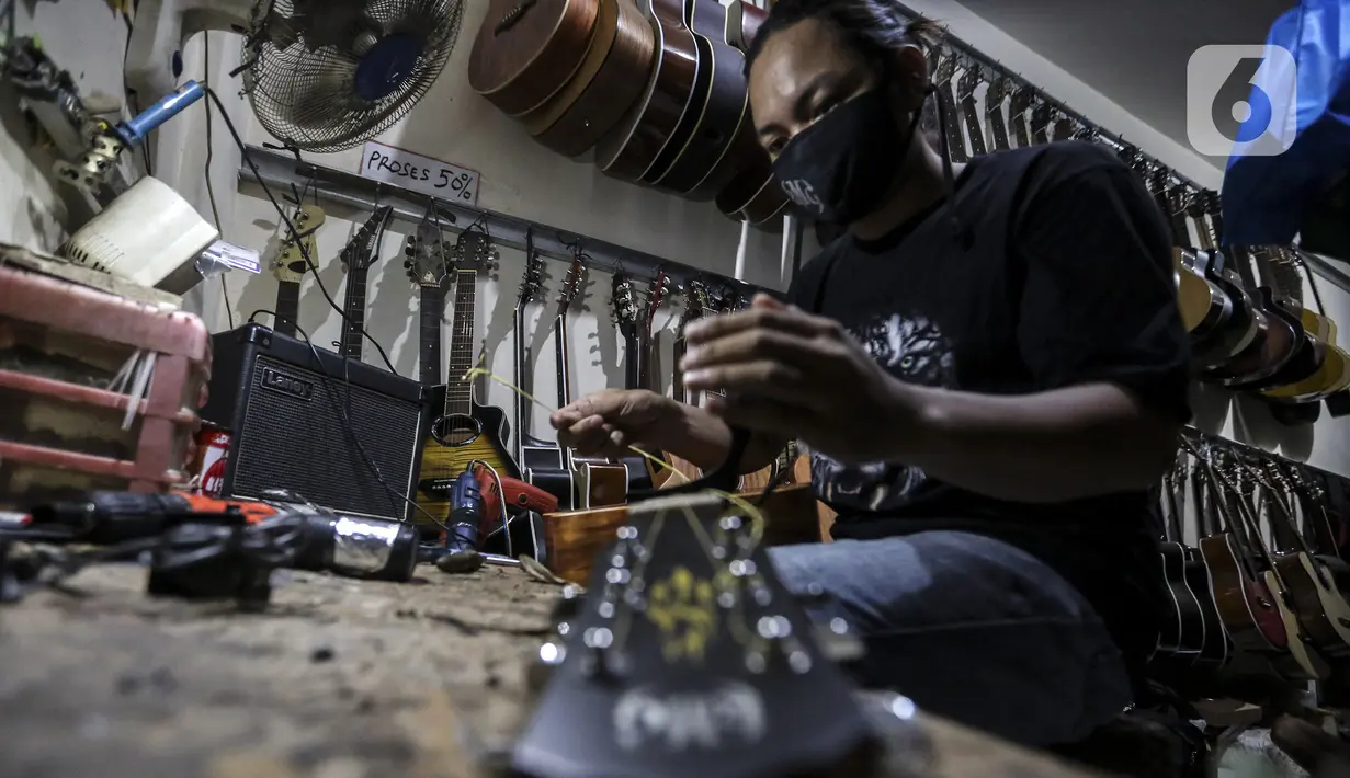 Harry saat mereparasi gitar klasik menjadi gitar listrik di toko kawasan Kedoya, Jakarta Barat, Selasa (9/2/2021). Toko bernama RMG ini merupakan toko servis dan reparasi gitar dengan berbagai merek. (Liputan6.com/Johan Tallo)