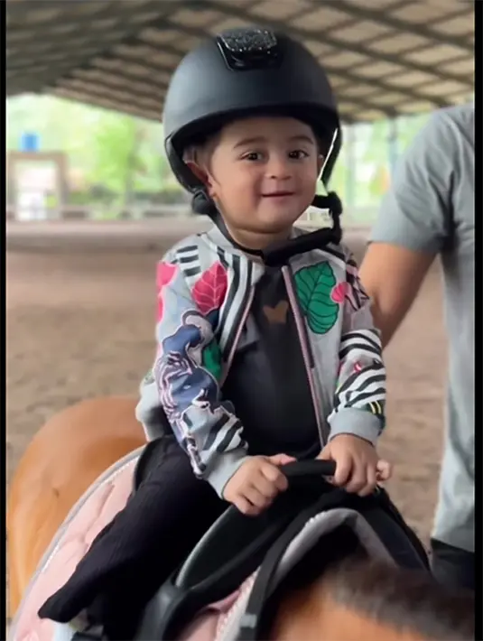 Berbeda dengan banyak anak kecil yang takut naik kuda, tapi baby Guzel tampak sangat menyukainya. Potret penampilannya senyum  saat naik kuda poni. [Instagram/marginw]