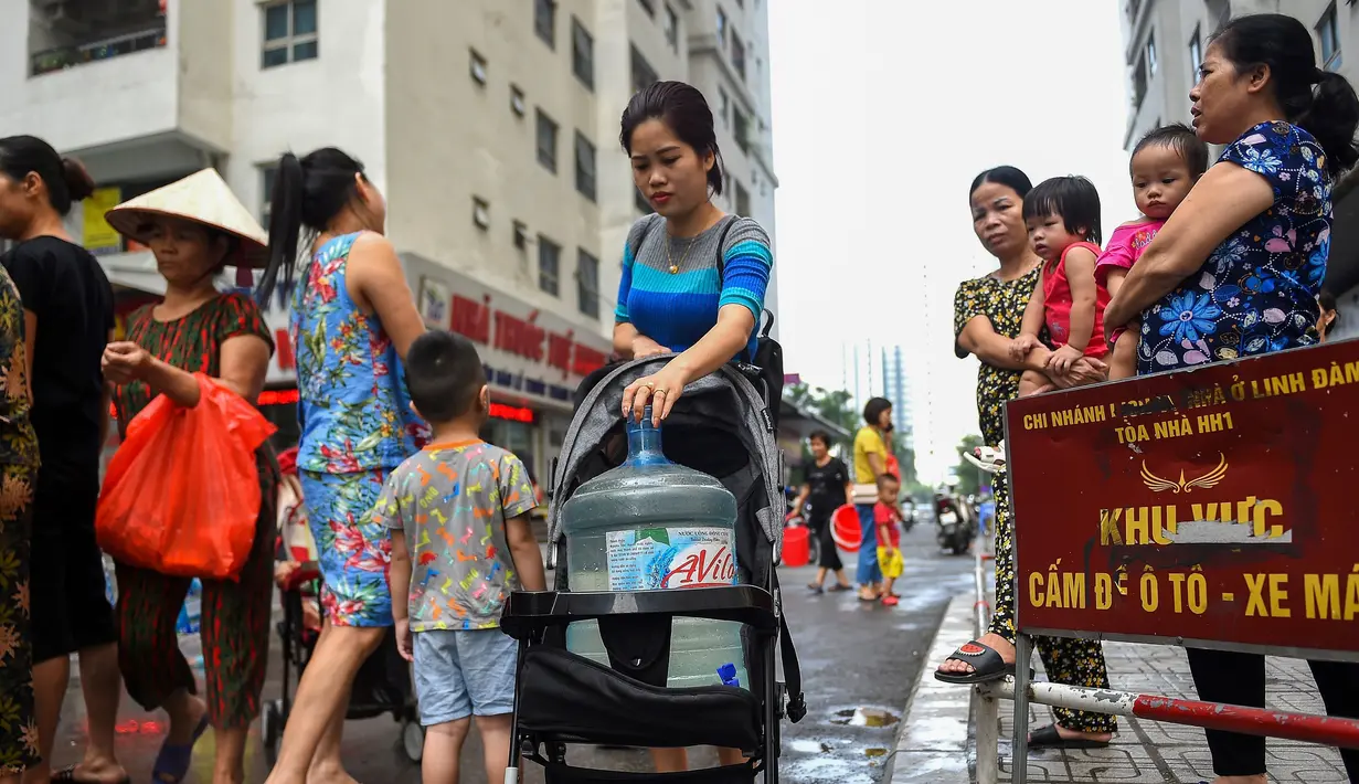 Warga membawa wadah berisi air usai mengisinya dari truk tangki pasokan pemerintah di Hanoi, Vietnam, Kamis (17/10/2019). Warga Hanoi melaporkan bahwa air ledeng yang mereka gunakan bau plastik terbakar. (Nhac NGUYEN/AFP)