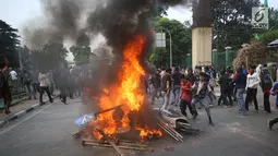 Pelajar membakar sepeda motor dan rambu lalu lintas saat berdemonstrasi di belakang Gedung DPR, Palmerah, Jakarta, Rabu (25/9/2019). Polda Metro Jaya mengamankan 200 pelajar yang berdemonstrasi. (Liputan6.com/Angga Yuniar)