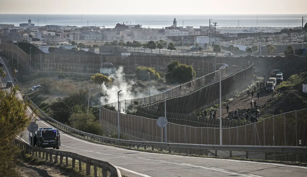 Pasukan keamanan di sisi perbatasan Maroko memaksa para migran untuk berbaring di depan pagar setelah menghentikan mereka melintasi pagar yang memisahkan kantong Spanyol Melilla dari Maroko, di Melilla, Spanyol  (3/3/2022). (AP Photo/Javier Bernardo)