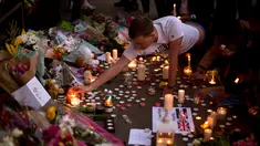 Seorang pria menyalakan lilin sehari setelah serangan bunuh diri di sebuah konser Ariana Grande di Albert Square, Manchester, Inggris, (23/5). Kejadian ini menyebabkan 22 orang tewas  dan melukai 119 lainnya. (AP Photo/Emilio Morenatti)