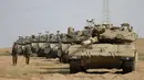 Tentara Israel berjalan melewati tank di dekat perbatasan Gaza-Israel, Jumat (19/10). Sekitar 60 tank dan kendaraan lapis baja pengangkut personel bergerak melalui jalan-jalan Israel menuju perbatasan Gaza. (AP Photo/Ariel Schalit)