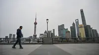 Seorang pria berjalan di sepanjang Sungai Huangpu di distrik Pudong yang dikunci sebagai tindakan melawan Covid-19, di Shanghai (28/3/2022).  Shanghai  lockdown setiap setengah kota secara bergiliran untuk tes Covid-19 massal mulai Senin (28/3/2022) di tengah lonjakan infeksi. (AFP/Hector Retamal)