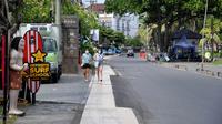 Pejalan kaki berjalan di sepanjang jalan utama yang sepi saat Pemberlakuan Pembatasan Kegiatan Masyarakat (PPKM) Level 3 di Kuta, Badung, Bali, Jumat (23/7/2021). Pemprov Bali tengah menerapkan PPKM Level 3. (SONNY TUMBELAKA/AFP)