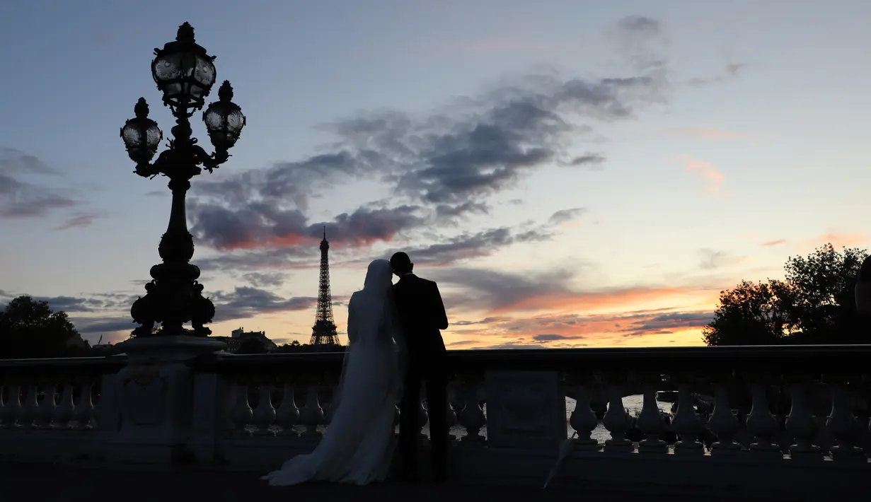 Sepasang calon pengantin melakukan foto prewedding dengan latar belakang Pyramide de Louvre di Paris, 9 Juli 2017. Bukan cuma menara Eiffel yang sudah amat terkenal itu, ibukota Perancis ini juga punya Piramida Louvre. (AFP PHOTO / LUDOVIC MARIN)