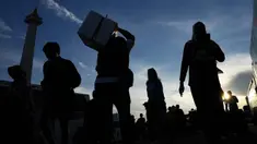 Orang-orang membawa barang-barang mereka saat tiba untuk perjalanan mudik gratis yang diselenggarakan oleh Pemerintah Provinsi Jakarta di Lapangan Monumen Nasional, Selasa 17 Maret 2026. (AP Photo/Achmad Ibrahim)